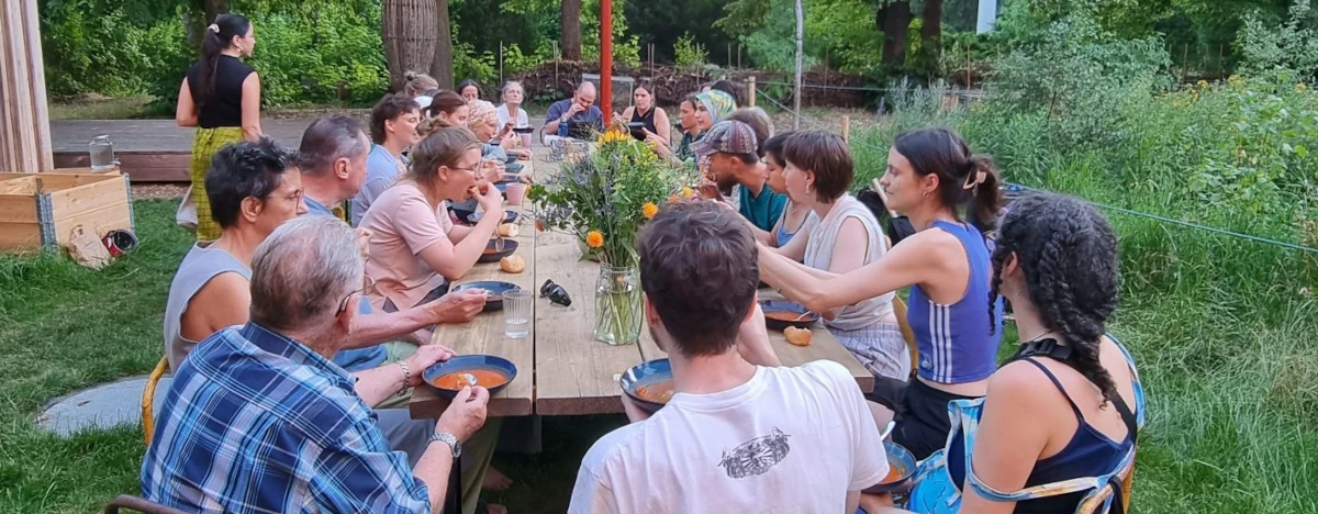 Menschen sitzen im Garten um einen langen Tisch herum